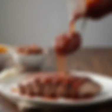 A rich close-up of Skylight Inn's signature barbecue sauce drizzling over pork.