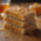 A close-up of honey energy bars stacked on a rustic wooden table with a drizzle of honey